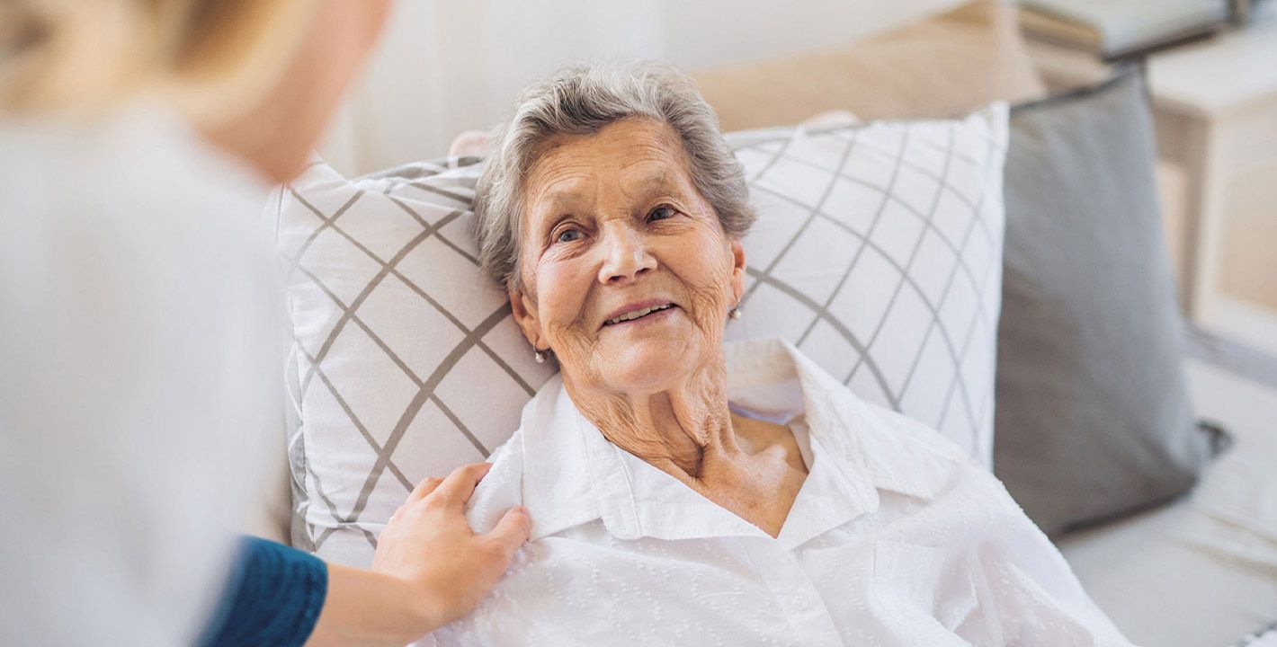 une auxiliaire de vie aide une dame âgée à se coucher