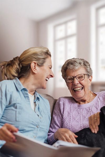 Une aide à domicile riant avec une personne âgée