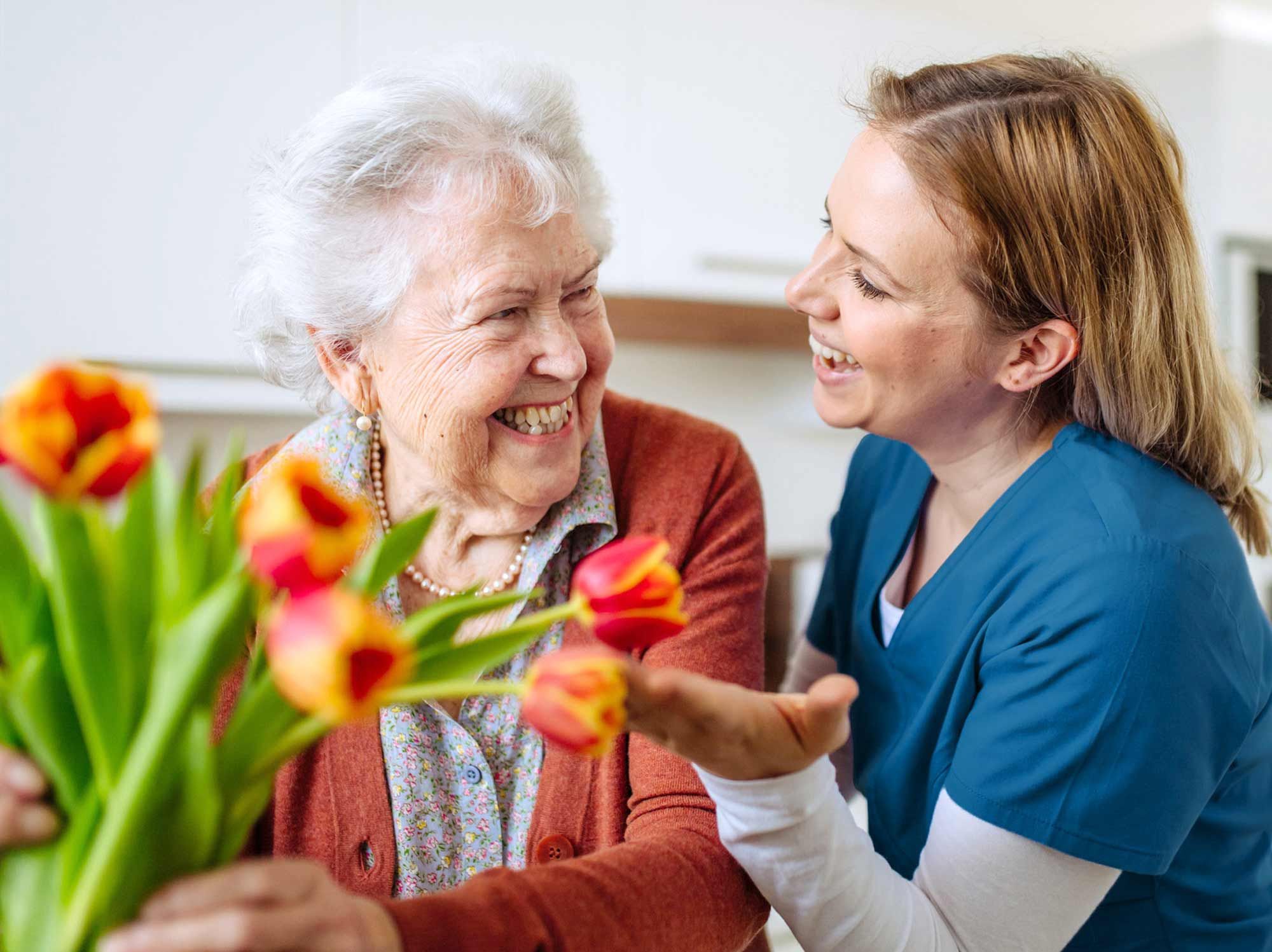 Une aide à domicile riant avec une personne âgée